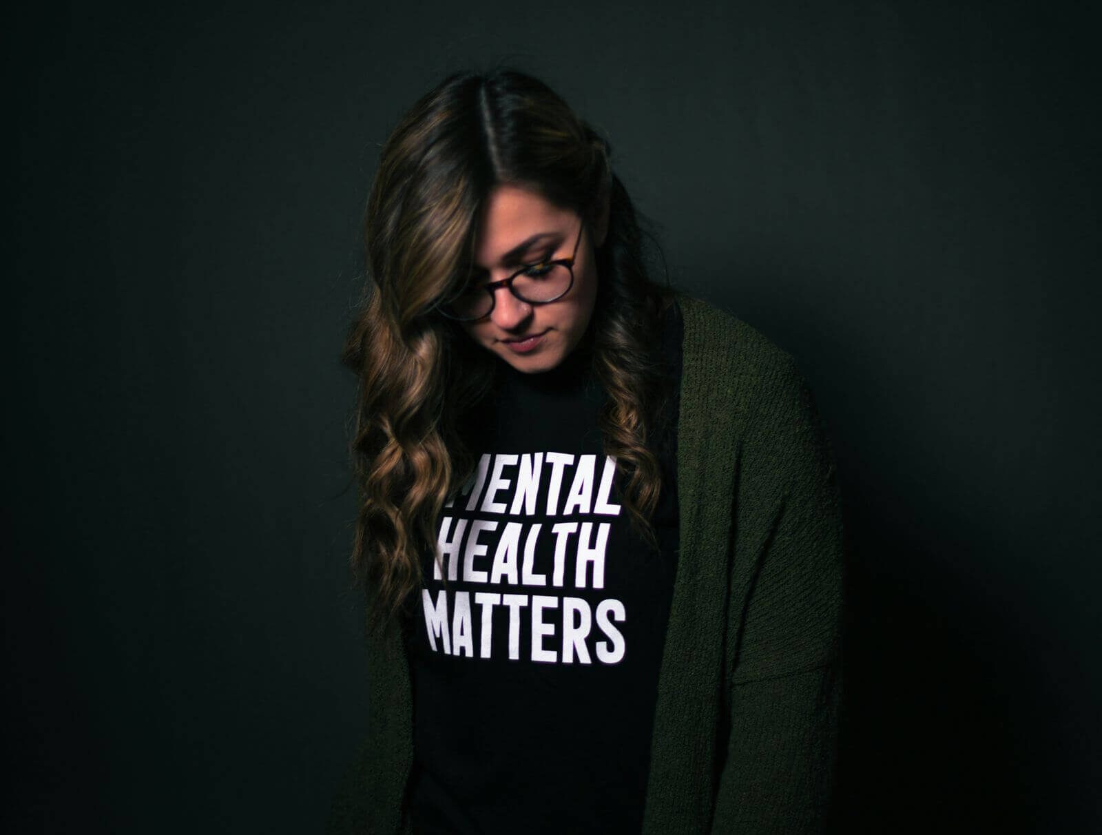 A woman wearing a black shirt that says "mental health matters" in white lettering.